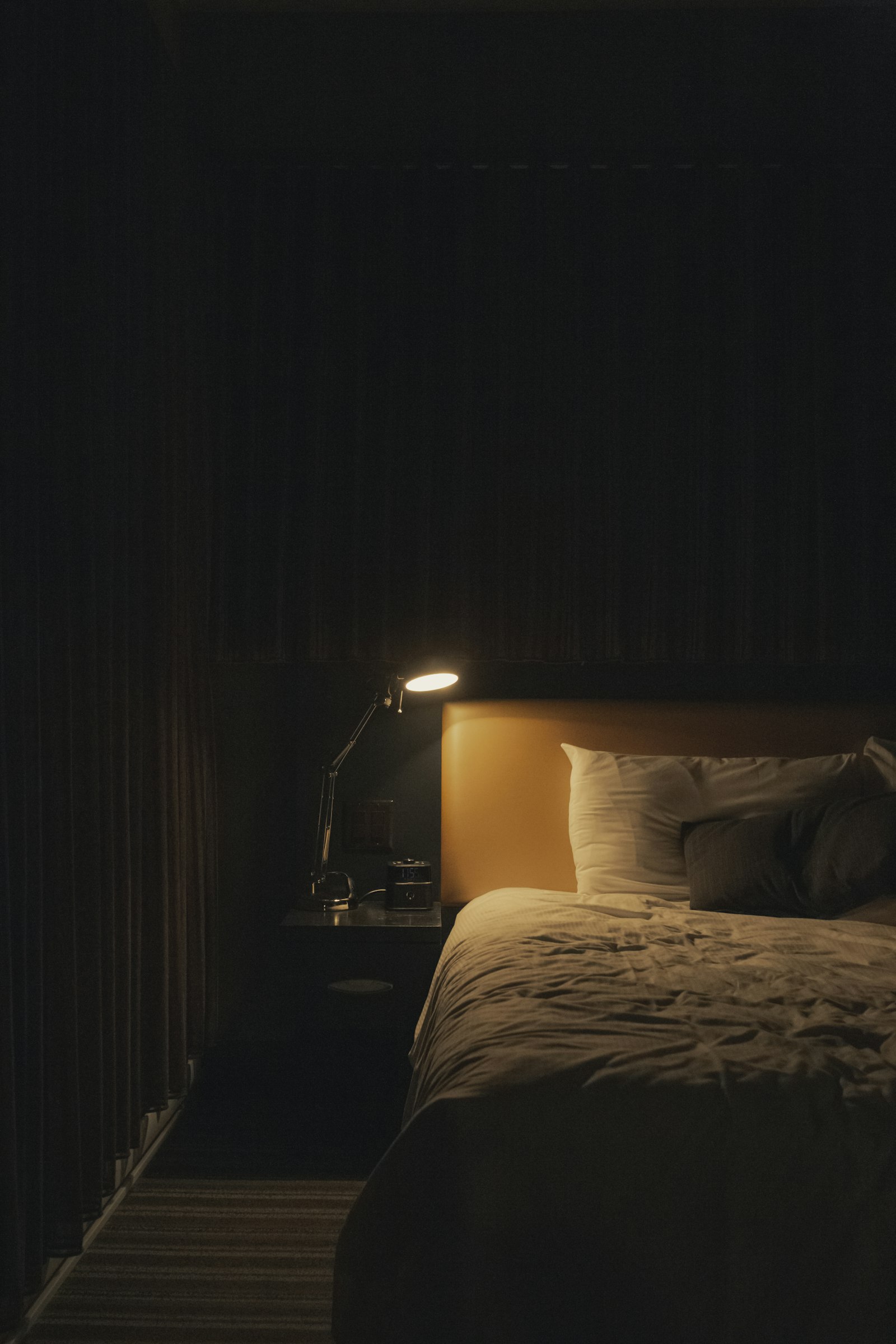 A softly lit bedside lamp next to a made bed at night